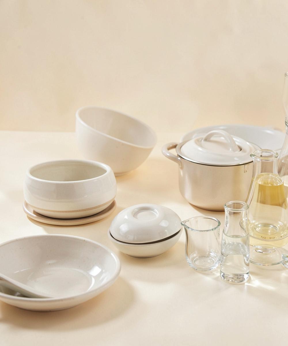 Ceramic bowls, cookware and glassware arranged on a warm surface